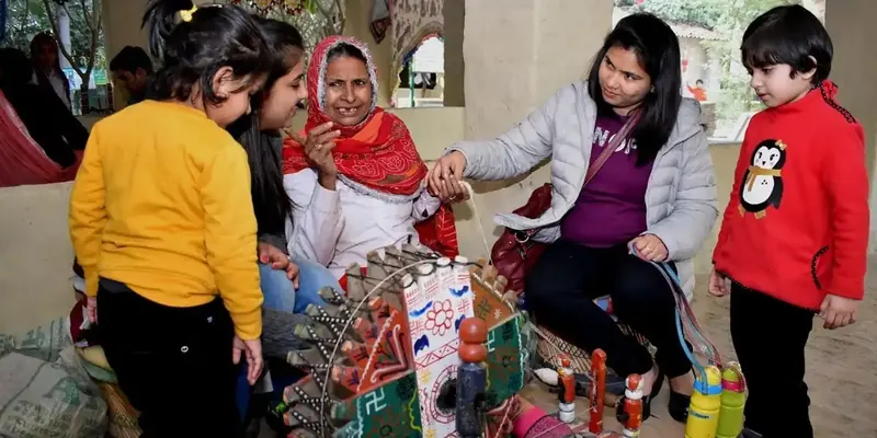 Children and adults gathered around a painted wooden wheel and small colourful toy figures