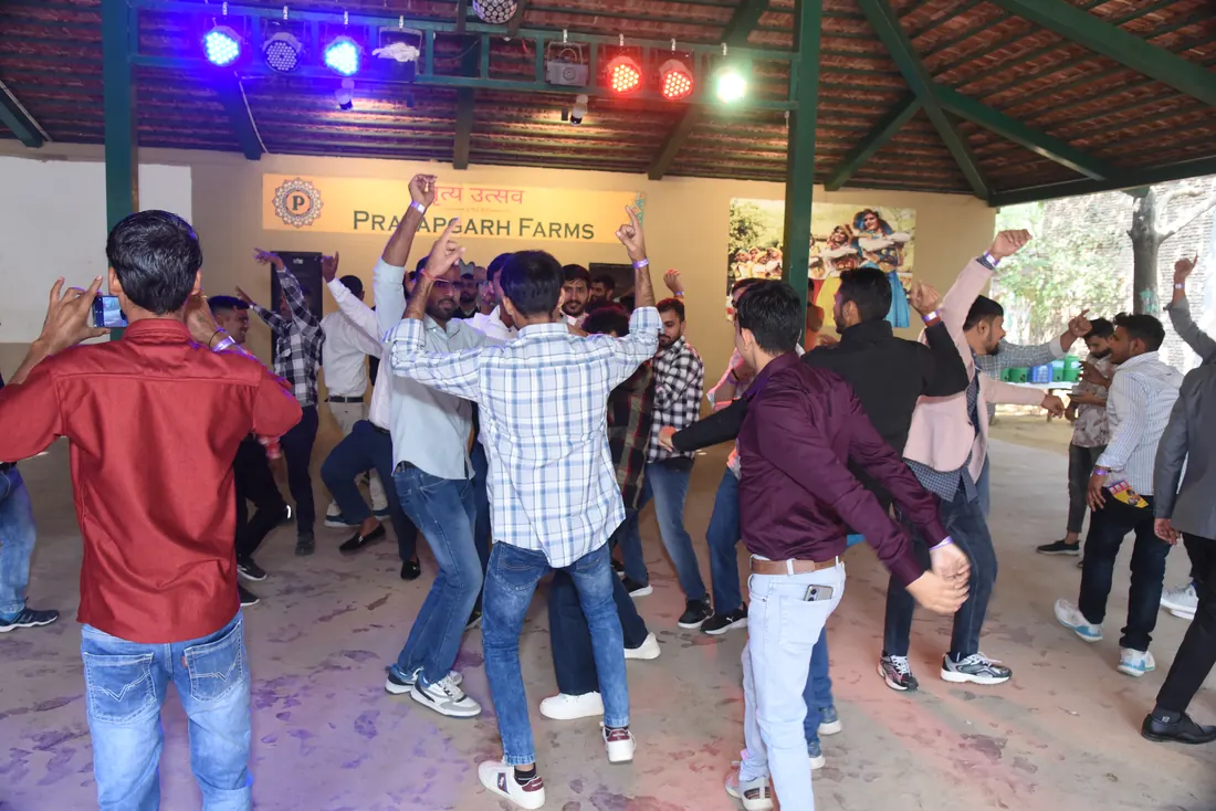 Employees dancing with arms raised on the hall's dance floor under coloured stage lights