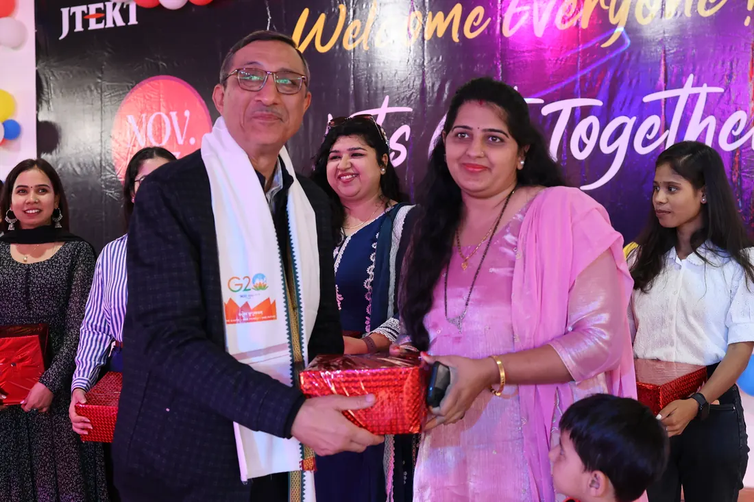 Manager handing a red gift box to a colleague on stage during the felicitation, with the team lined up behind them