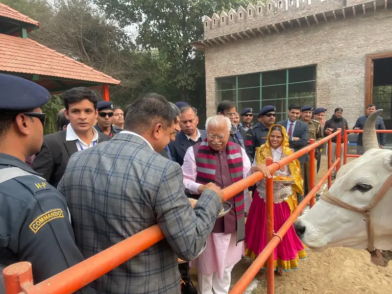 Haryana Chief Minister Manohar Lal at the cattle enclosure during his visit to Pratapgarh Farms on 13 January 2023, with farm staff and a woman in Haryanvi dress beside a white bull
