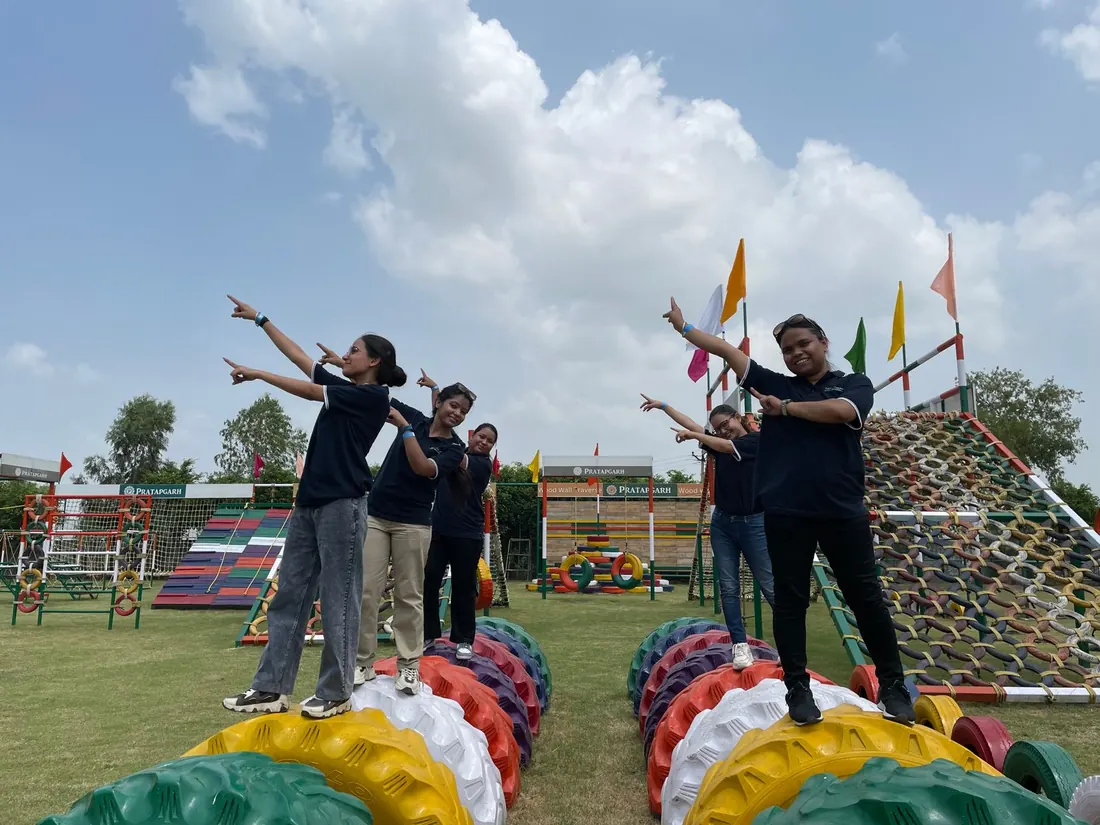 Group in black t-shirts posing on rows of painted tyres in front of the tyre climbing wall